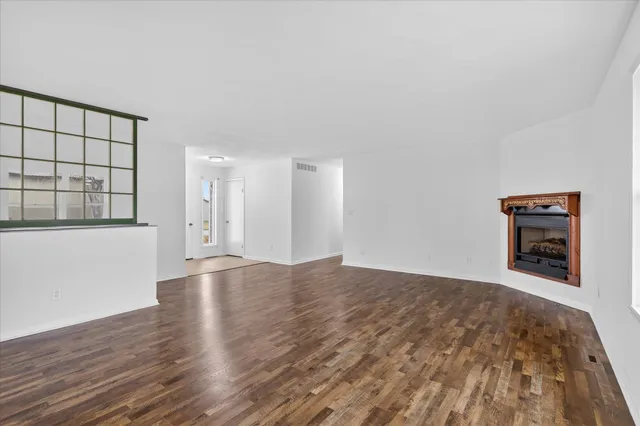 a view of a big room with wooden floor and windows