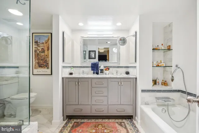 a bathroom with a granite countertop sink a toilet a mirror and shower