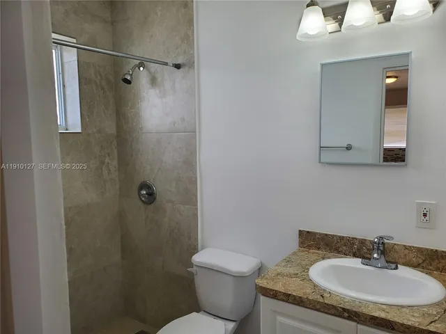 a bathroom with a granite countertop sink toilet and shower