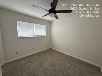 an empty room with a ceiling fan and window