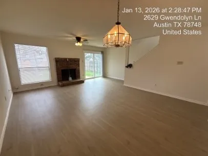 an empty room with wooden floor fireplace and windows