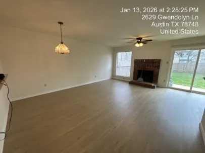an empty room with windows fireplace and fans