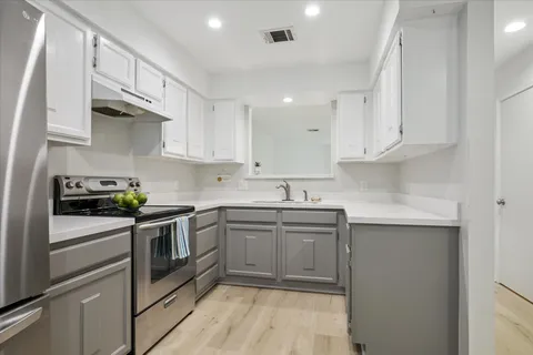 a kitchen with cabinets stainless steel appliances a sink and wooden floor