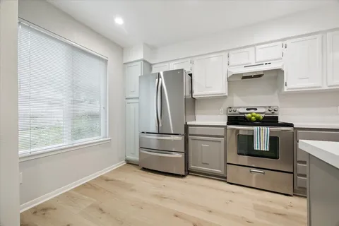 a kitchen with granite countertop a refrigerator and a stove top oven