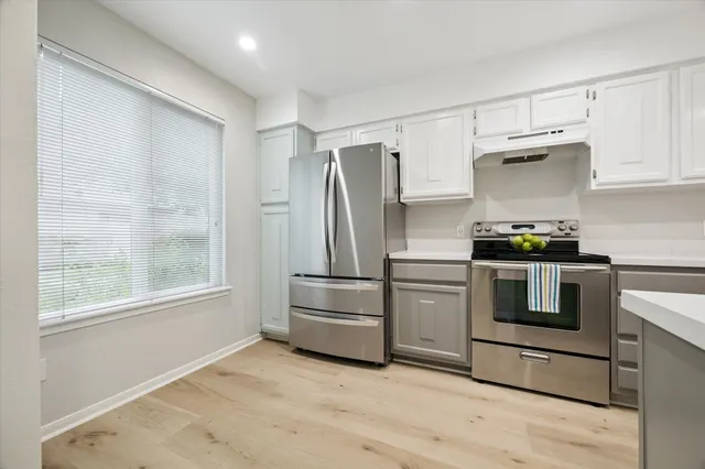 a kitchen with granite countertop a refrigerator and a stove top oven