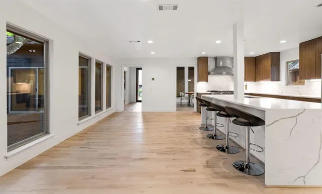 a room with stainless steel appliances kitchen island granite countertop a table and chairs in it