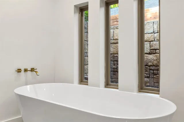 a white bath tub sitting in a bathroom next to a window