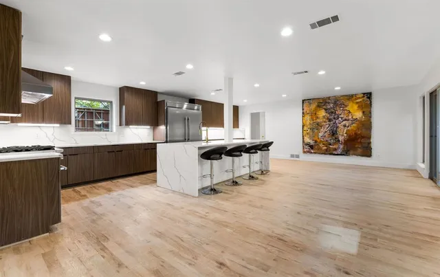 a living room with stainless steel appliances kitchen island granite countertop furniture a rug and a large window