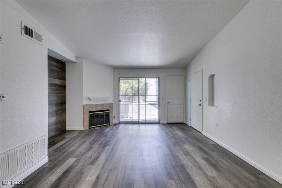 3318 North Decatur Boulevard, Unit 2138 Las Vegas, NV 89130 - Photo 10 of 40 Unfurnished living room featuring a fireplace, dark wood-style floors, and baseboards
