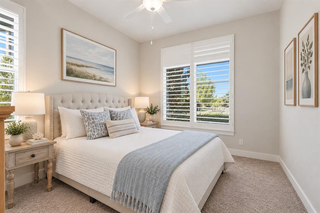 8408 Twistpine Road Frisco, TX 75035 - Photo 19 of 38 Tufted headboard, dual windows with plantation shutters, ceiling fan, neutral wall tones, and carpeted flooring