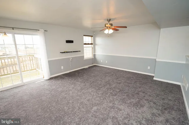 an empty room with windows and chandelier fan