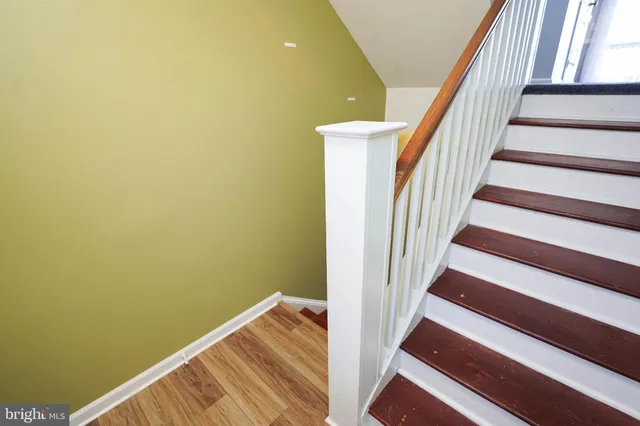 a view of staircase with wooden floor and white walls
