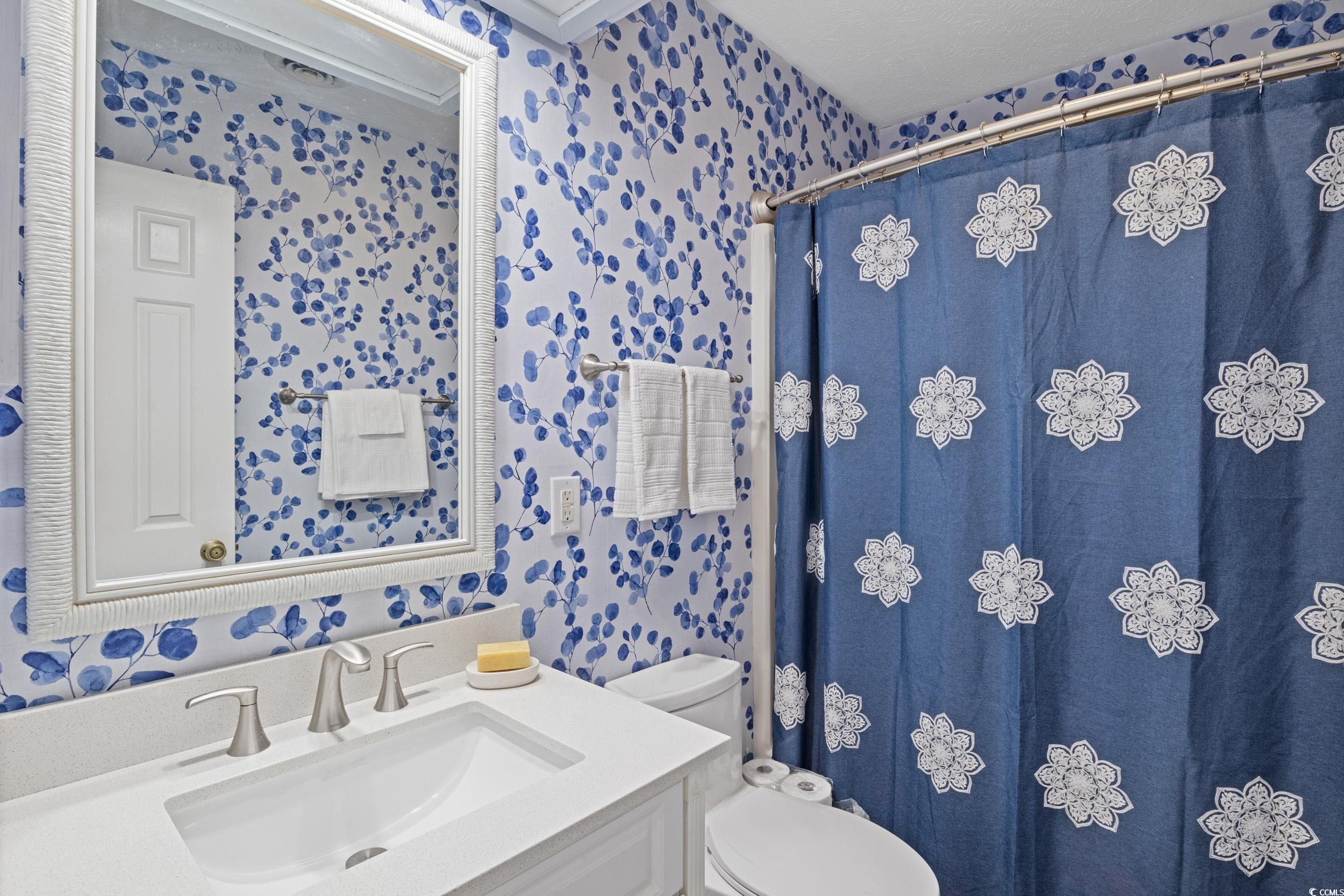 830 44th Avenue North, Unit S4 Myrtle Beach, SC 29577 - Photo 15 of 31 Bathroom featuring wallpapered walls, vanity, and a stall shower