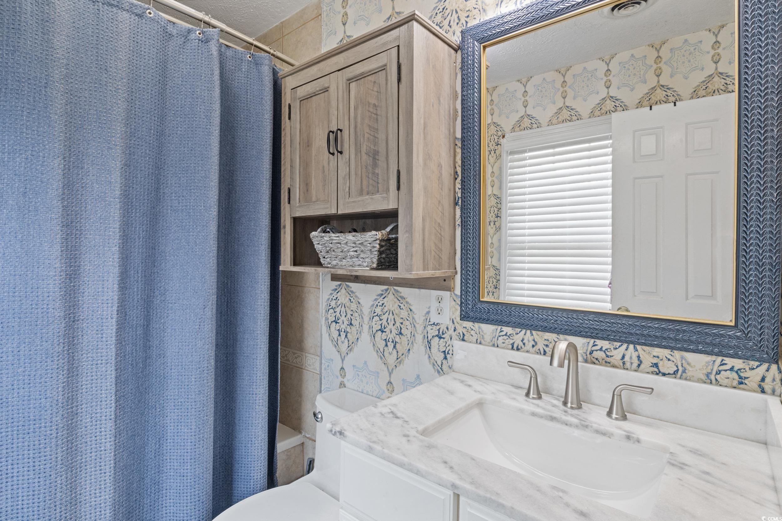 830 44th Avenue North, Unit S4 Myrtle Beach, SC 29577 - Photo 19 of 31 Bathroom with wallpapered walls, vanity, and shower / tub combo with curtain