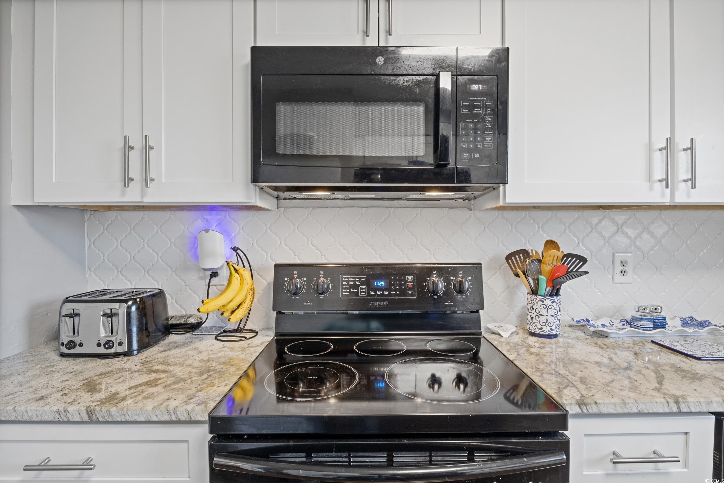 830 44th Avenue North, Unit S4 Myrtle Beach, SC 29577 - Photo 4 of 31 Kitchen with black appliances, white cabinets, backsplash, and light stone counters