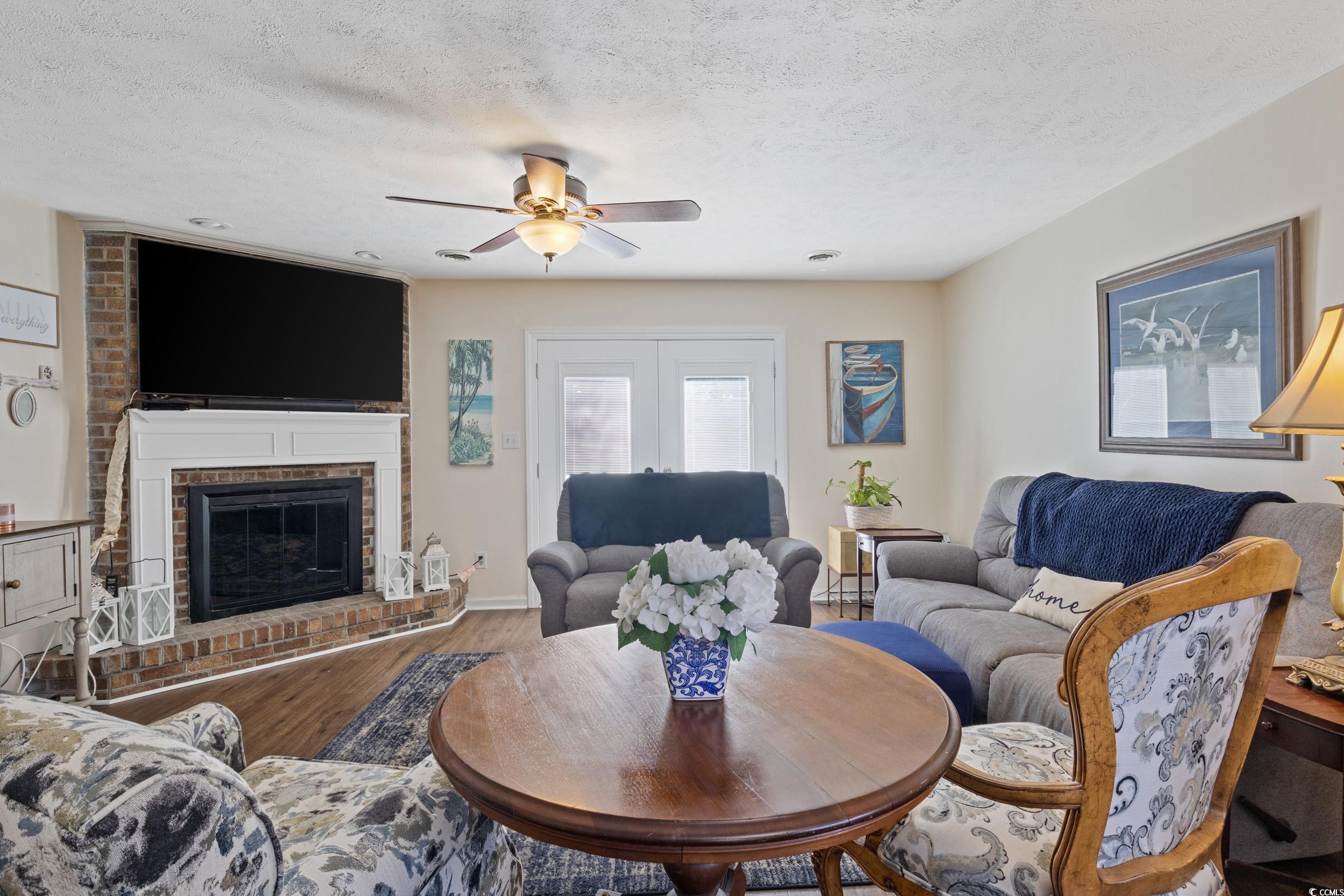 830 44th Avenue North, Unit S4 Myrtle Beach, SC 29577 - Photo 6 of 31 Living room featuring wood finished floors, a textured ceiling, a brick fireplace, and a ceiling fan