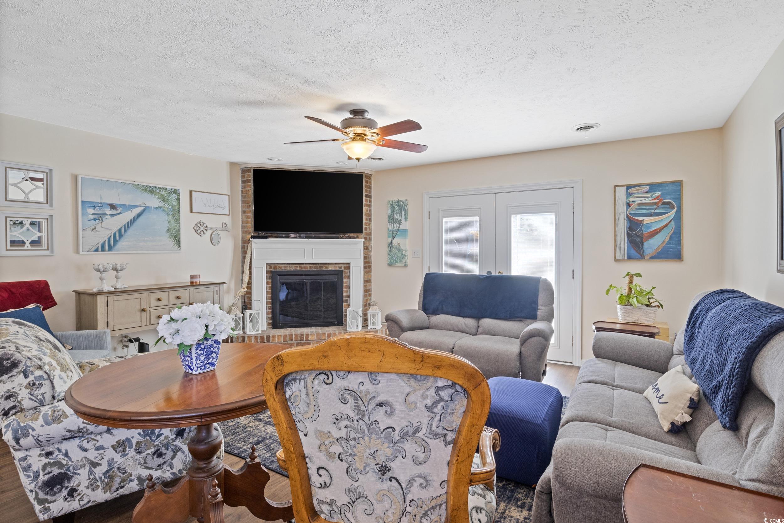 830 44th Avenue North, Unit S4 Myrtle Beach, SC 29577 - Photo 7 of 31 Living area with a fireplace, a textured ceiling, ceiling fan, wood finished floors, and french doors