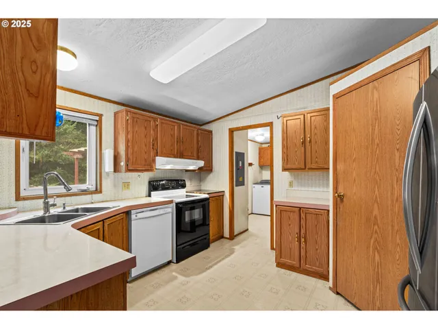 a kitchen with stainless steel appliances granite countertop a refrigerator a sink dishwasher a stove and a dining table with large window