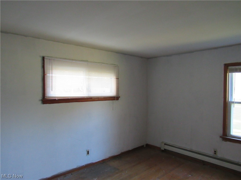 6986 Reed Road Conneaut, OH 44030 - Photo 13 of 22 Unfurnished room with a baseboard radiator and dark hardwood floors