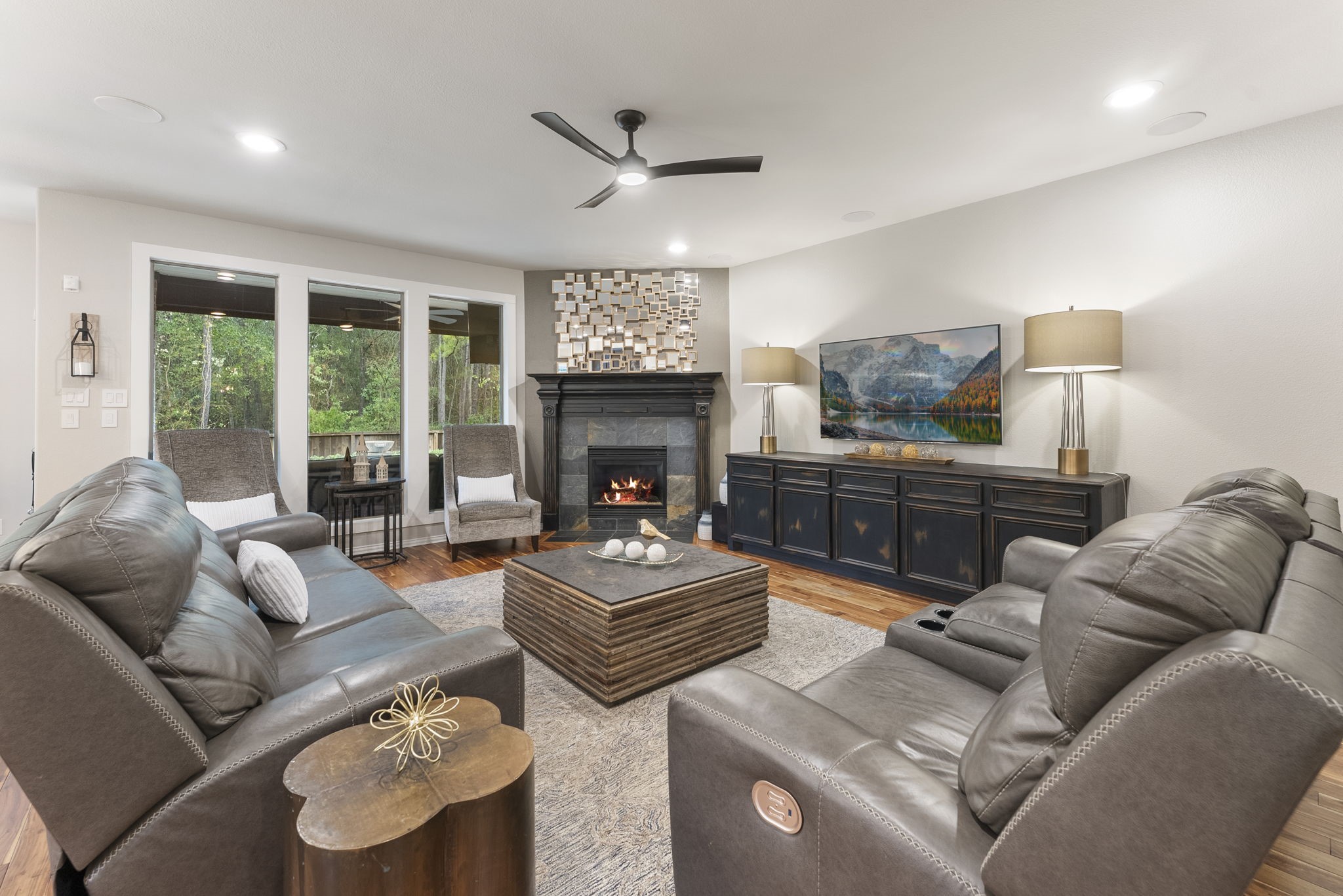 27614 Colin Springs Lane Spring, TX 77386 - Photo 11 of 47 Spacious Family Room located at the back of the home featuring a wall of tall windows with views of the pool and wooded greenbelt, a gas fireplace with custom mantle, lower built-ins for storage, wood flooring, ceiling speakers, and an updated ceiling fan!