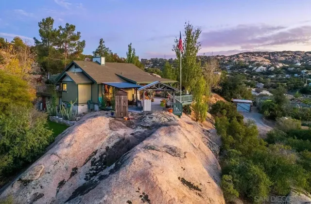 a front view of a house with a yard and mountain view in back