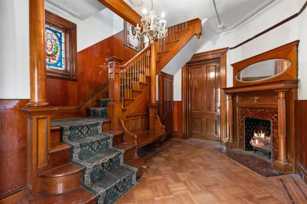 a view of a livingroom with a fireplace wooden floor door and a chandelier