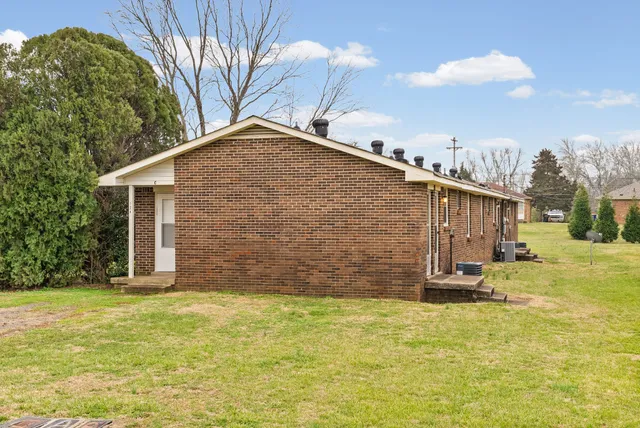 a backyard of a house with table and chairs under an umbrella