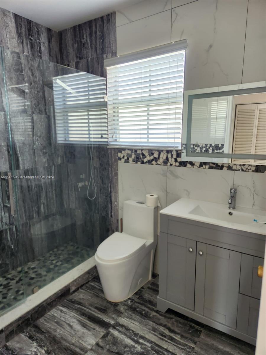 a bathroom with a granite countertop sink toilet a mirror and shower