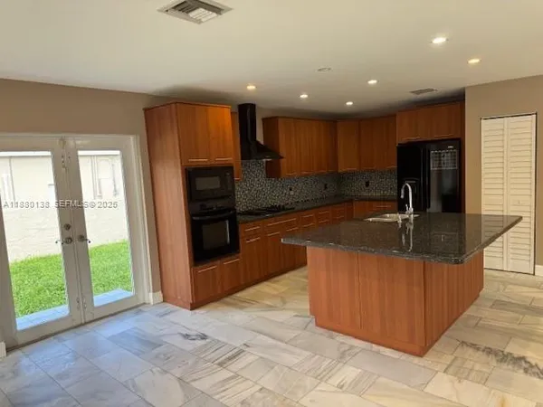 a kitchen with stainless steel appliances granite countertop a sink and a refrigerator