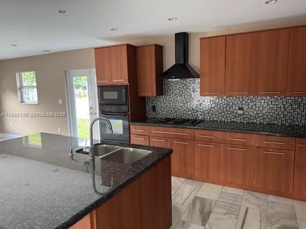 a kitchen with granite countertop stainless steel appliances wooden cabinets and a sink