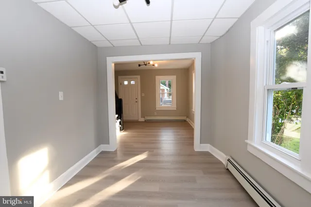 a view of a hallway with wooden floor and chandelier