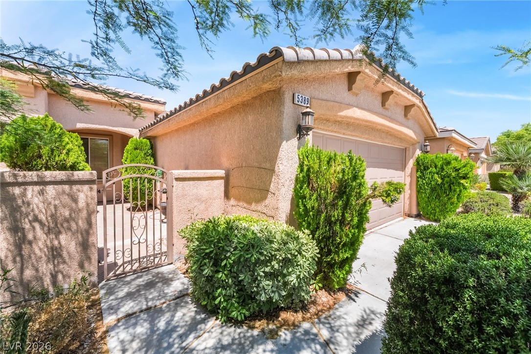 5389 Progresso Street Las Vegas, NV 89135 - Photo 5 of 41 An inviting facade featuring well-maintained landscaping and an arched entry gate.