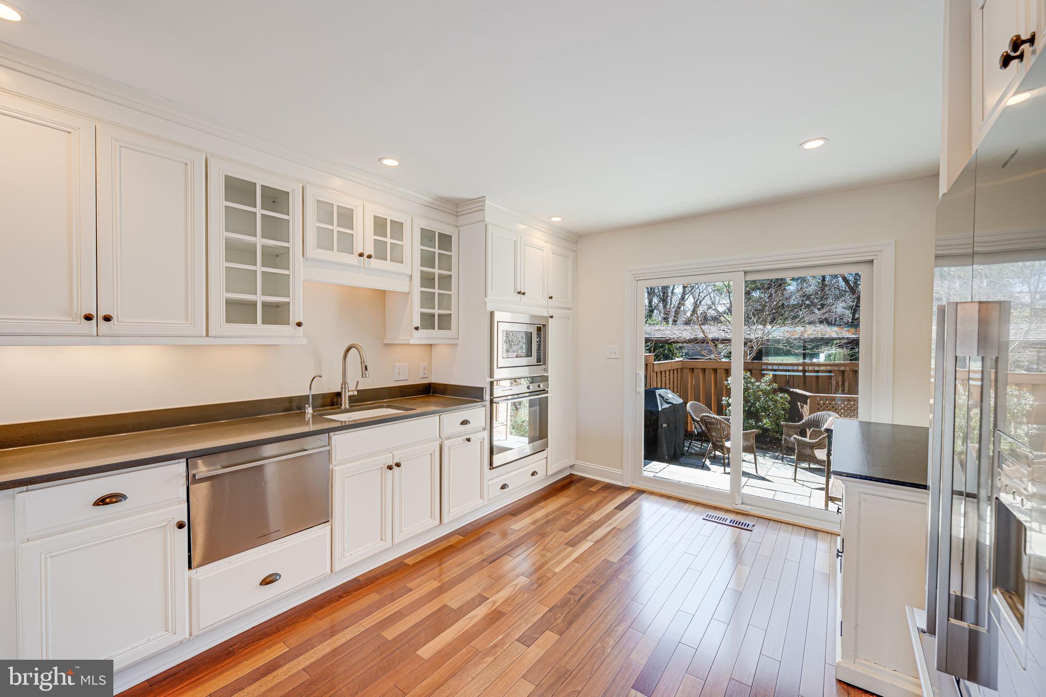 11222 Lagoon Lane Reston, VA 20191 - Photo 8 of 20 a kitchen with stainless steel appliances wooden floor and white cabinets