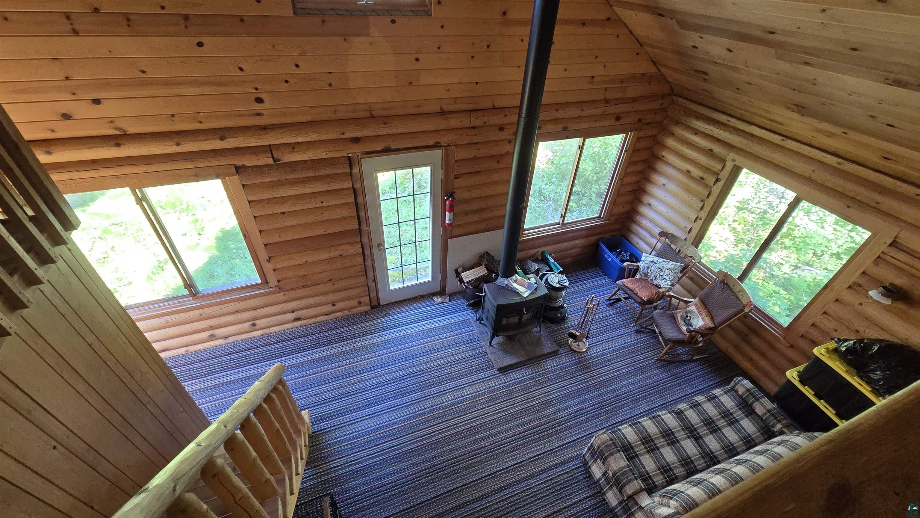 Tbd33 Tbd33 Donovan Point Orr, MN 55771 - Photo 14 of 50 Carpeted living area featuring rustic walls, a wood stove, and a vaulted wooden ceiling