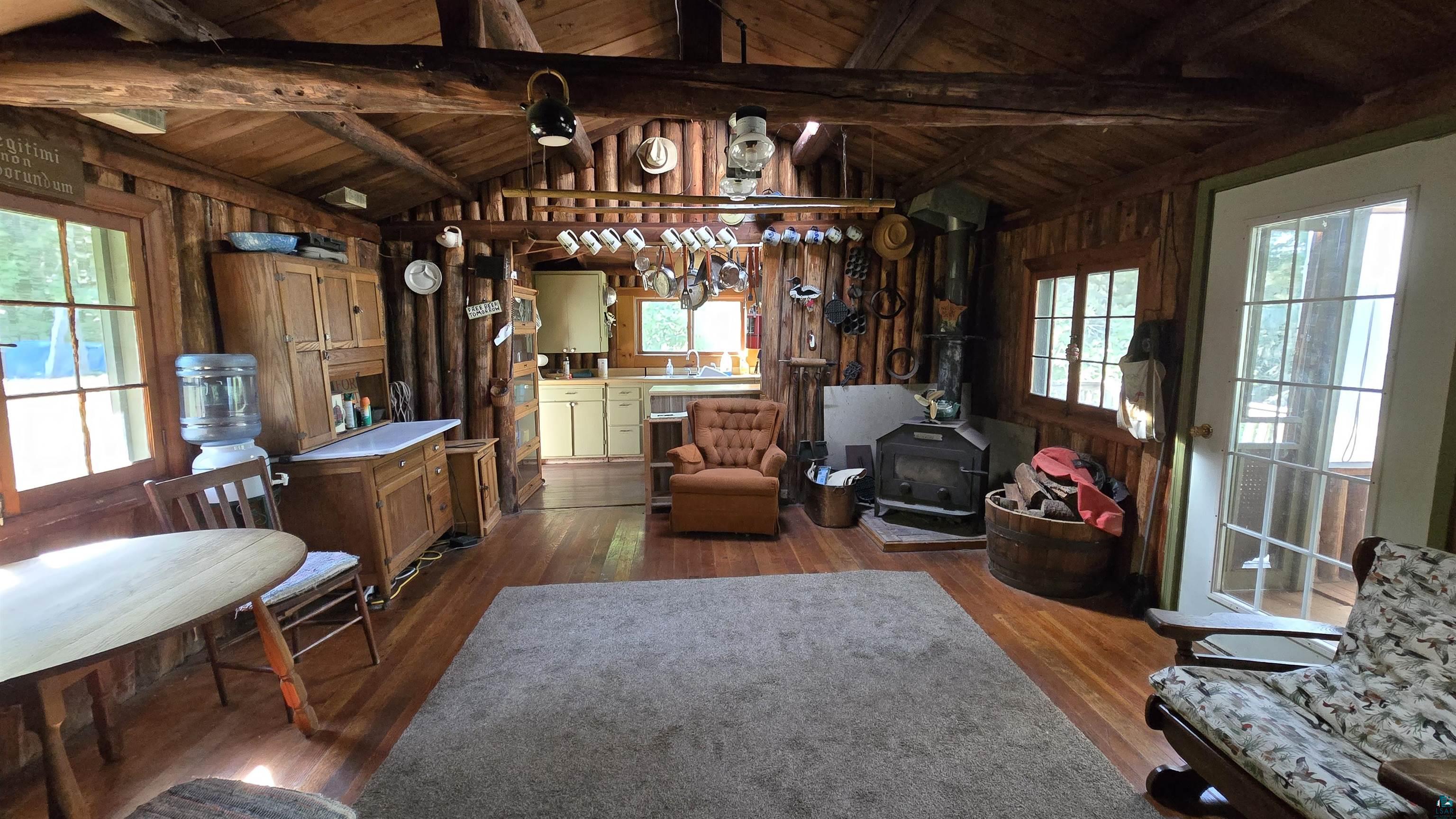 Tbd33 Tbd33 Donovan Point Orr, MN 55771 - Photo 22 of 50 Living room featuring wood walls, a wood ceiling with exposed beams, hardwood / wood-style floors, healthy amount of natural light, and a wood stove