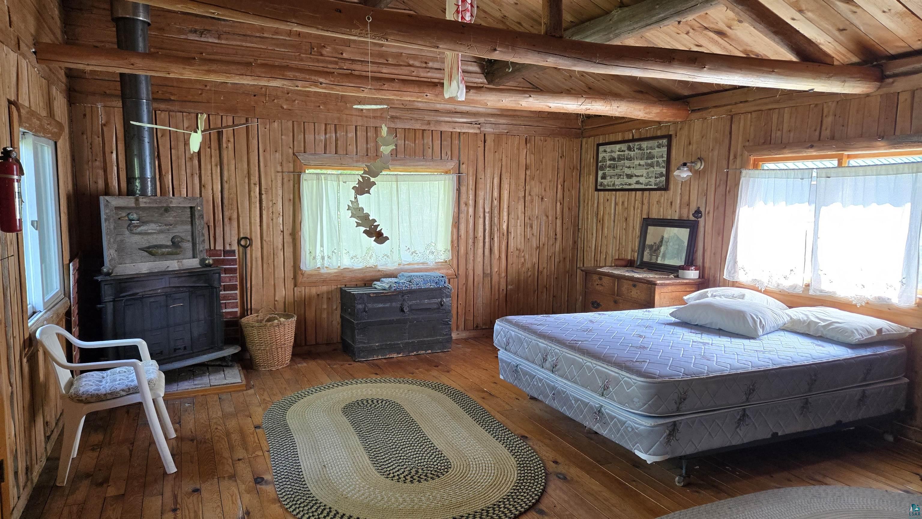 Tbd33 Tbd33 Donovan Point Orr, MN 55771 - Photo 26 of 50 Bedroom featuring hardwood / wood-style floors, a wood stove, wood ceiling, wood walls, and vaulted ceiling with beams