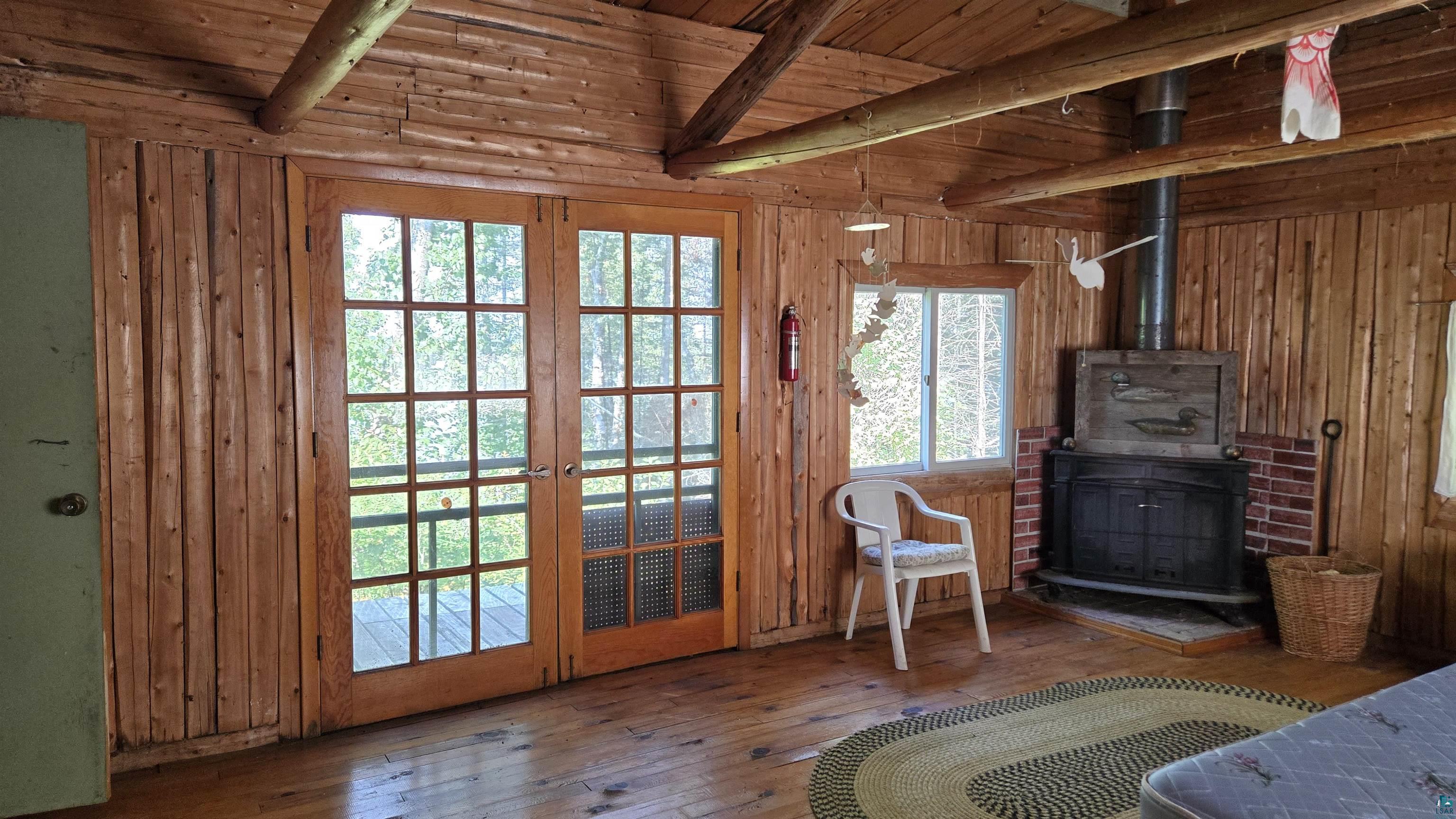 Tbd33 Tbd33 Donovan Point Orr, MN 55771 - Photo 28 of 50 Sitting room with a wood stove, hardwood / wood-style flooring, a wood ceiling with exposed beams, french doors, and wood walls