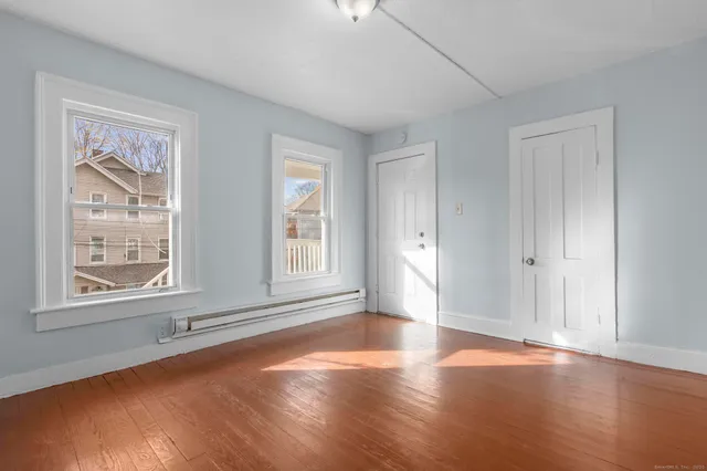 a view of an empty room with wooden floor and a window