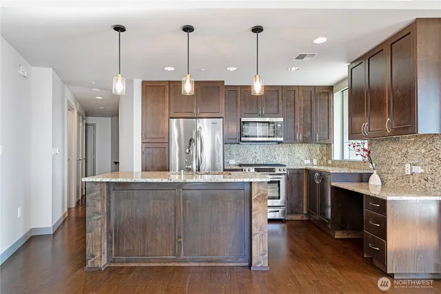 a kitchen with kitchen island granite countertop wooden cabinets and a fireplace