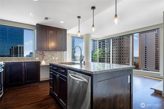 a kitchen with stainless steel appliances granite countertop a sink a stove and a wooden floors
