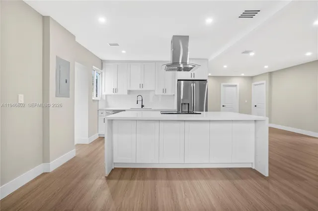 a kitchen with kitchen island white cabinets and stainless steel appliances