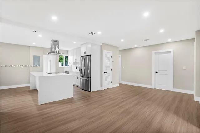 a view of a kitchen with refrigerator and wooden floor