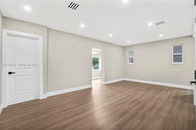a view of an empty room with wooden floor and closet