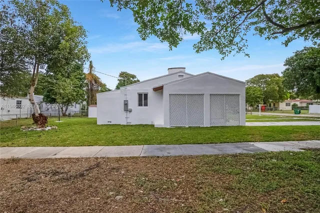 a view of a house with a yard and a large tree
