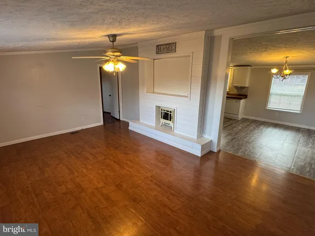 a view of an empty room with wooden floor and a fireplace