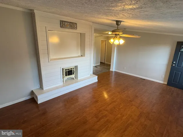 a view of a livingroom with wooden floor a ceiling fan and staircase