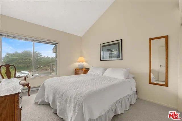 a bedroom with a bed and a lamp on dresser