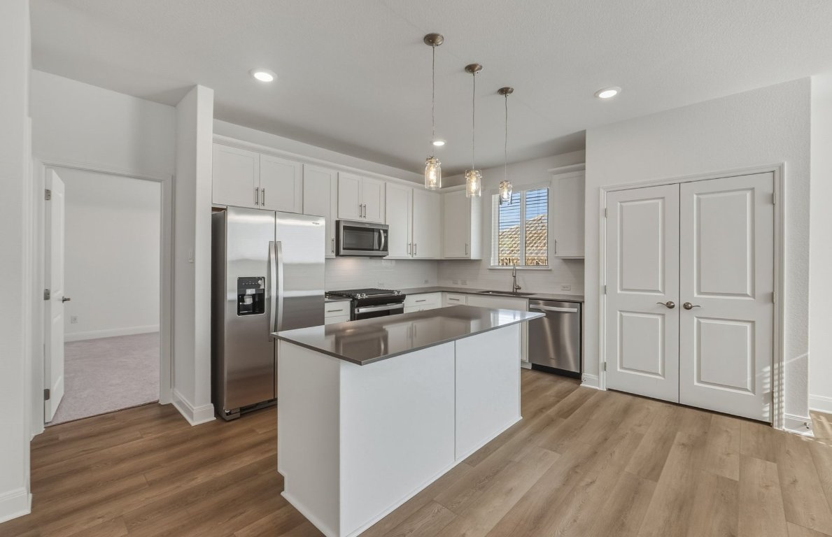 216 Daniels Dusty Trail Georgetown, TX 78626 - Photo 5 of 23 a kitchen with stainless steel appliances granite countertop a refrigerator a sink dishwasher a stove and white countertops with wooden floor