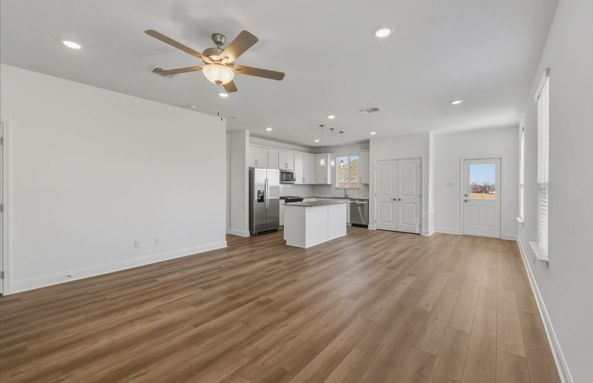 216 Daniels Dusty Trail Georgetown, TX 78626 - Photo 6 of 23 a view of an empty room with wooden floor and a kitchen
