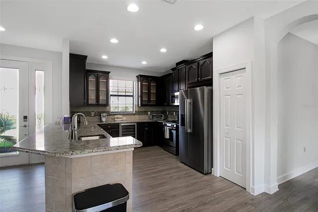 a kitchen with stainless steel appliances granite countertop refrigerator a sink wooden cabinets and a wooden floor